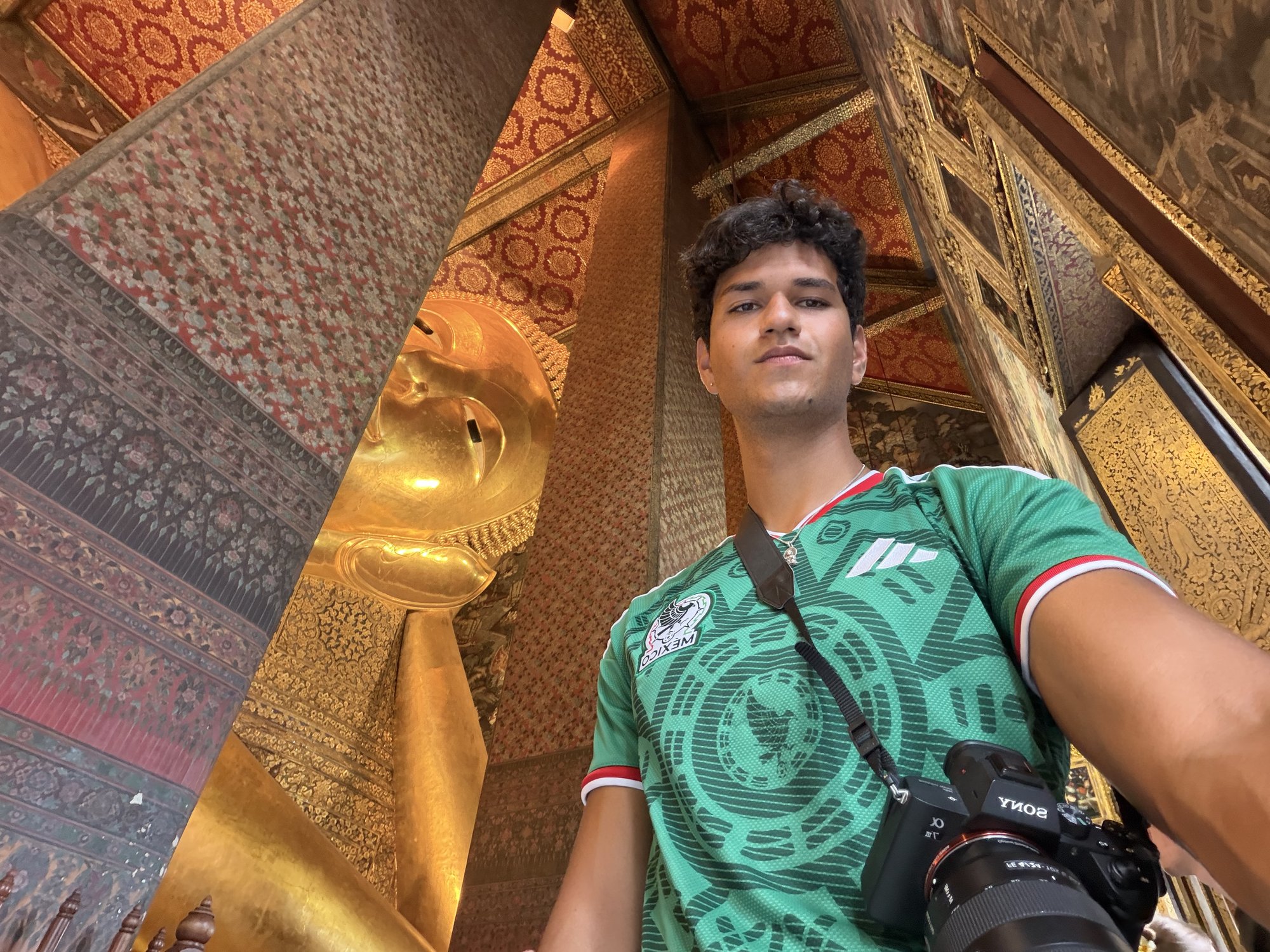 Matías Marcín taking a selfie inside a temple in front of a gold reclining Buddha statue